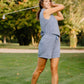 Woman playing golf on a grassy course with trees in the background